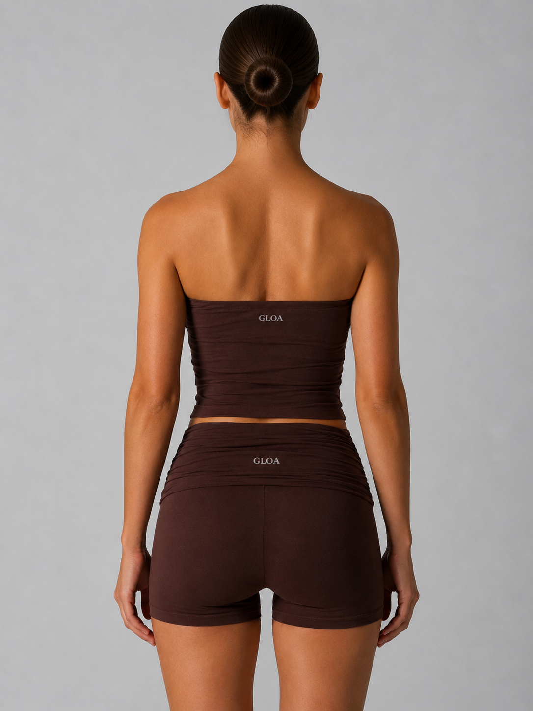 Woman wearing a brown strapless top and shorts set with 'GLOA' branding on a gray background