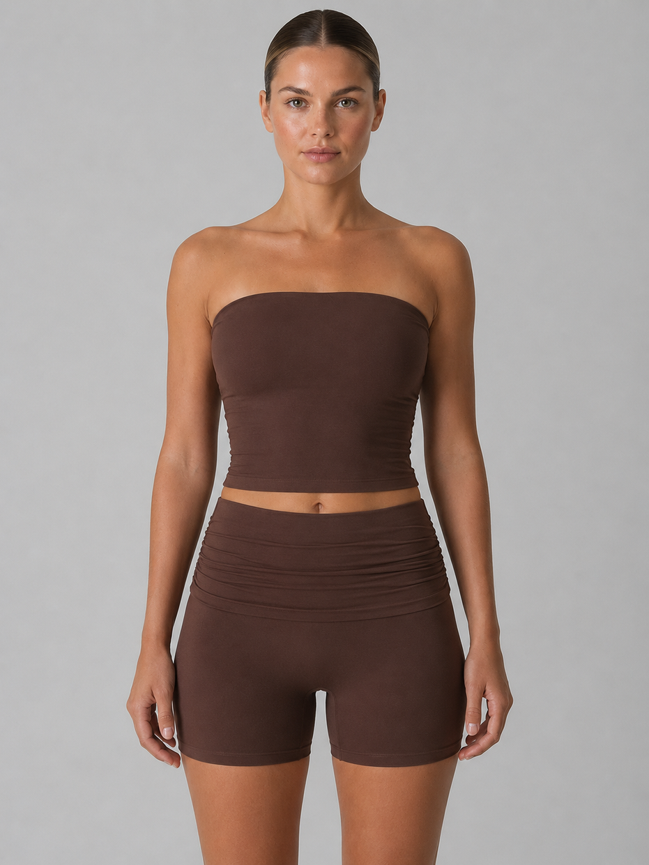 Woman wearing a brown strapless top and shorts set on a gray background