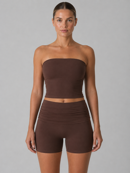 Woman wearing a brown strapless top and shorts set on a gray background