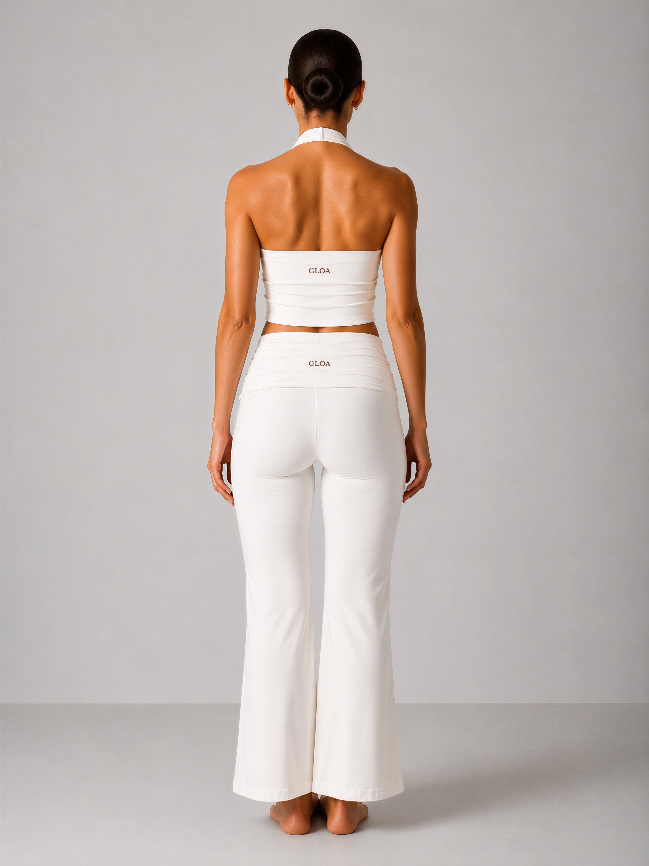 Woman wearing a white outfit with 'Gloa' branding on a plain background