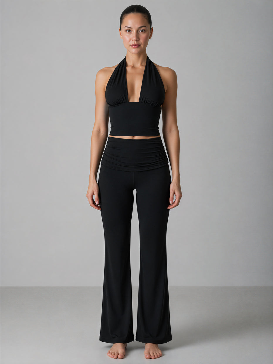 Woman wearing a black halter top and black pants on a gray background