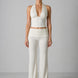 Woman wearing a white halter top and wide-leg pants against a gray background