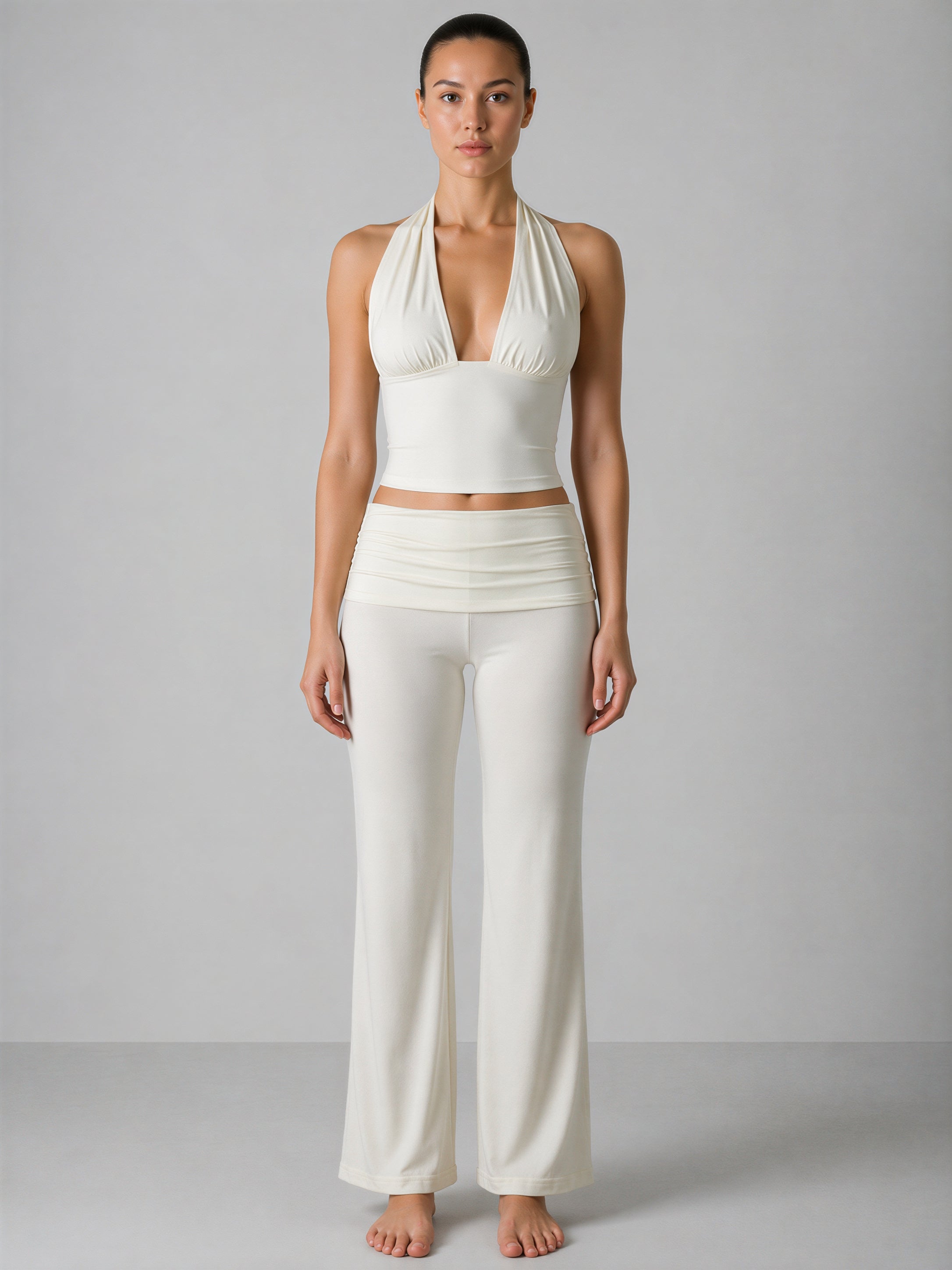 Woman wearing a white halter top and wide-leg pants against a gray background