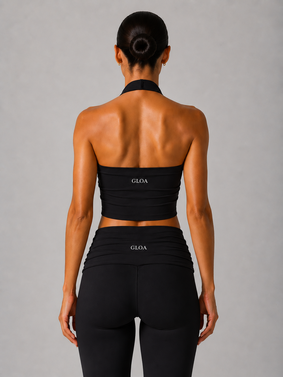 Person wearing a black halter and leggings with 'GLOA' branding on a gray background