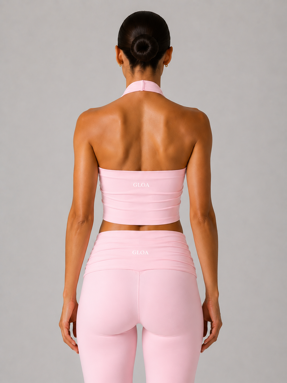 Person wearing a pink halter and leggings set on a gray background