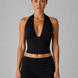 Woman wearing a black halter top and leggings against a gray background