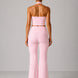 Woman wearing a pink strapless top and high-waisted pants against a gray background