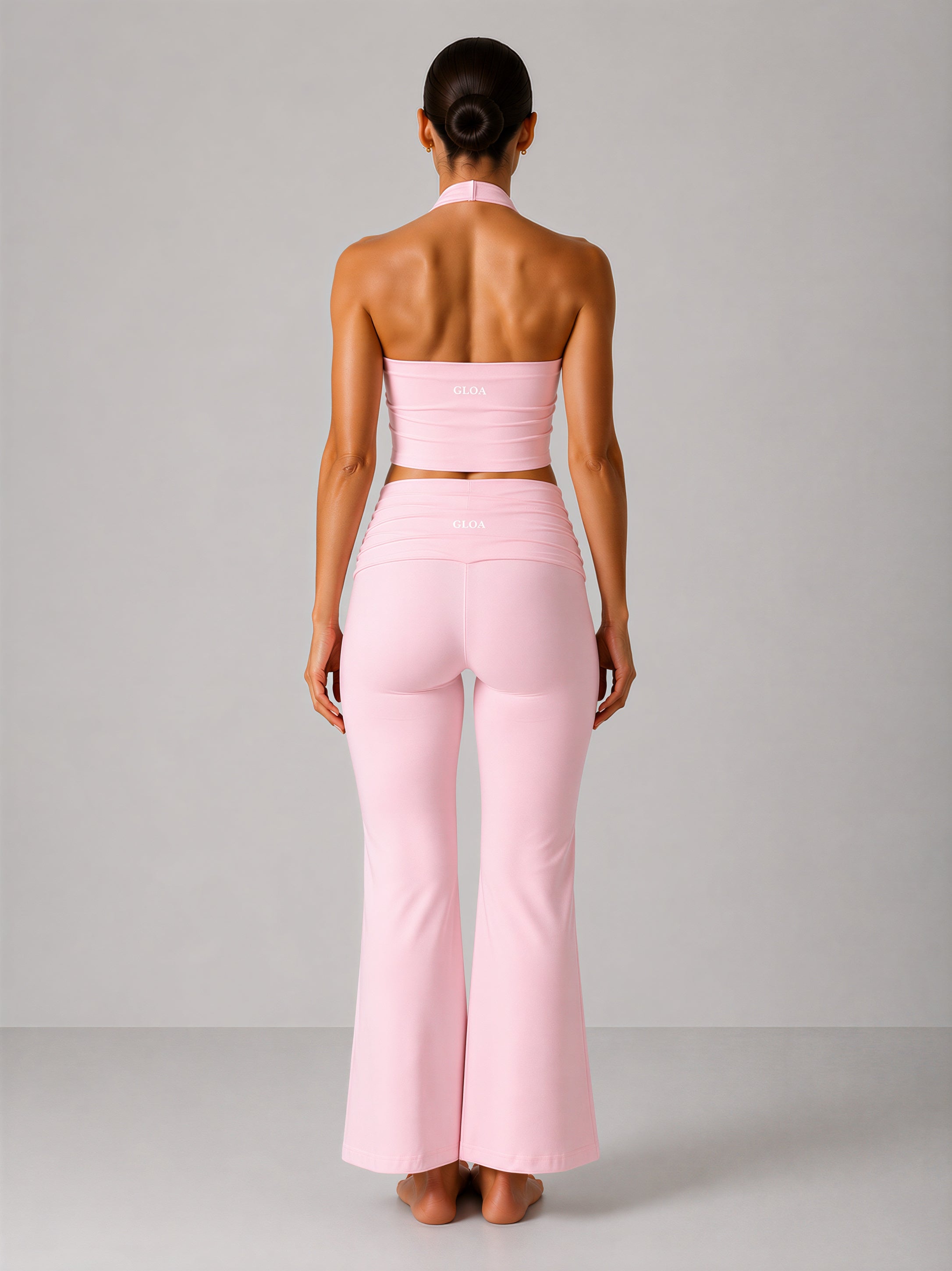Woman wearing a pink strapless top and high-waisted pants against a gray background