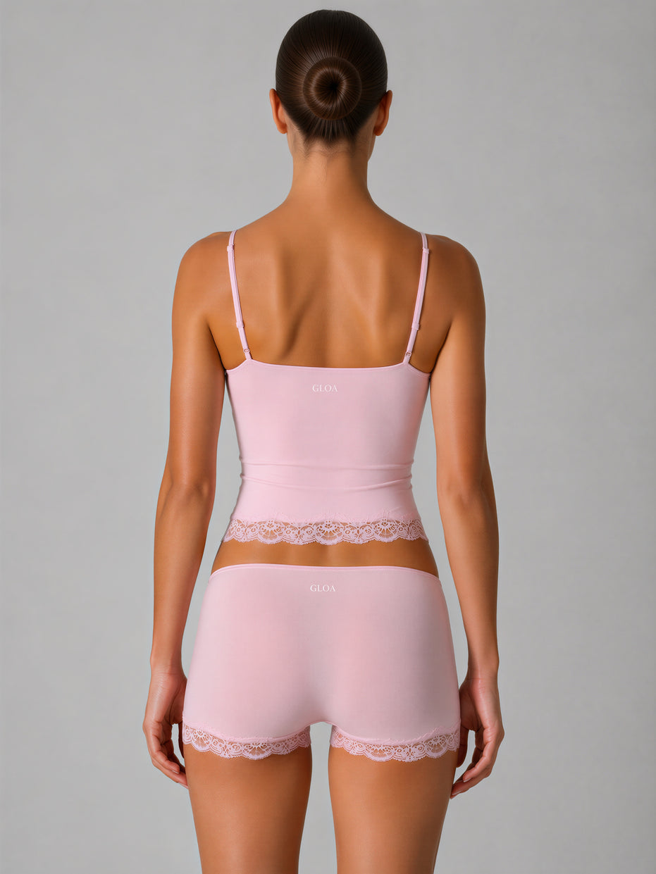 Woman wearing a pink lingerie set with lace details on a gray background