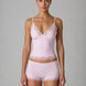 Woman wearing a light pink lingerie set with lace details on a gray background