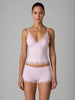 Woman wearing a light pink lingerie set with lace details on a gray background