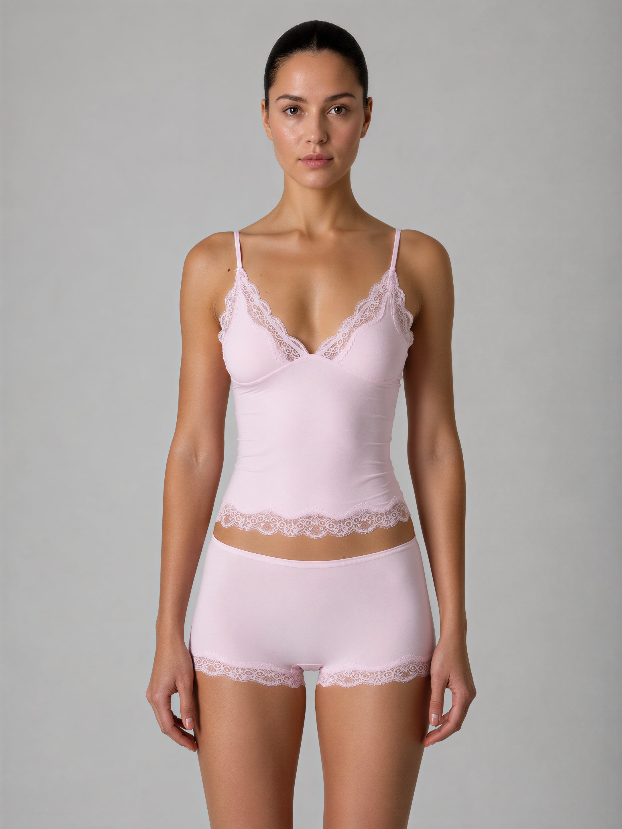 Woman wearing a light pink lingerie set with lace details on a gray background