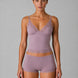 Woman wearing a matching lavender bra and panties set against a gray background