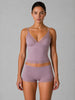 Woman wearing a matching lavender bra and panties set against a gray background