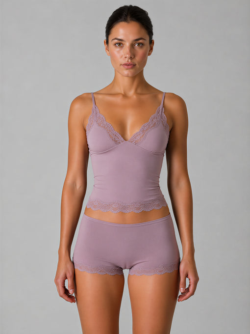Woman wearing a matching lavender bra and panties set against a gray background