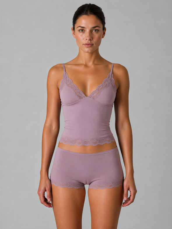 Woman wearing a matching lavender bra and panties set against a gray background