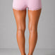 Person wearing pink lace-trimmed shorts on a gray background