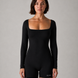 Woman wearing a black bodysuit with 'GLOA' branding on a gray background