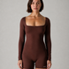 Woman wearing a brown bodysuit against a gray background