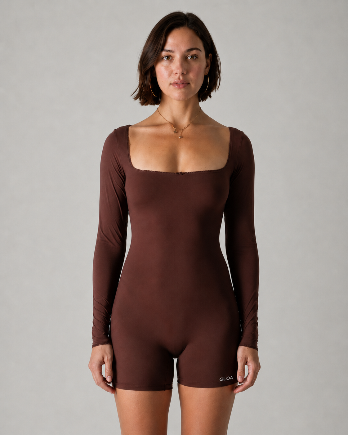 Woman wearing a brown bodysuit against a gray background