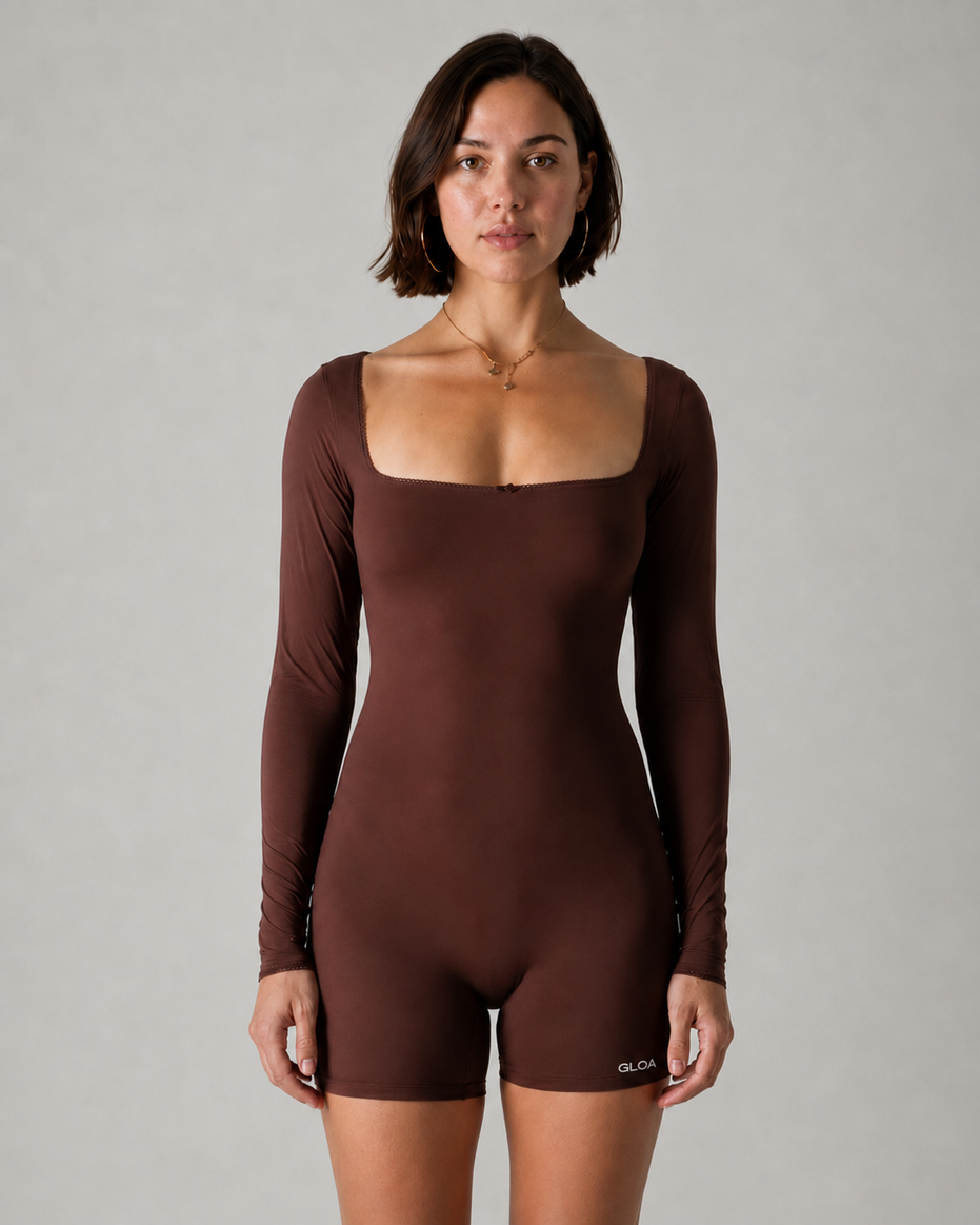 Woman wearing a brown bodysuit against a gray background