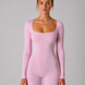 Woman wearing a pink bodysuit against a gray background